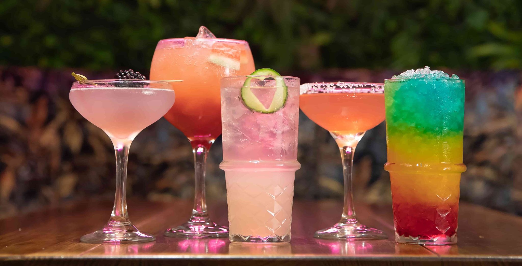selection of colourful cocktails in front of neon S & L sign