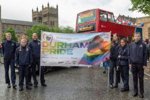 county durham fire fighters holding walkergate durham pride banner in front of Durham Catherdral in 2022
