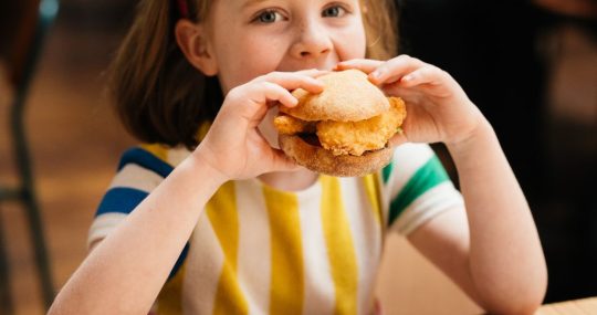 young girl biting into ask italian chicken sandwich