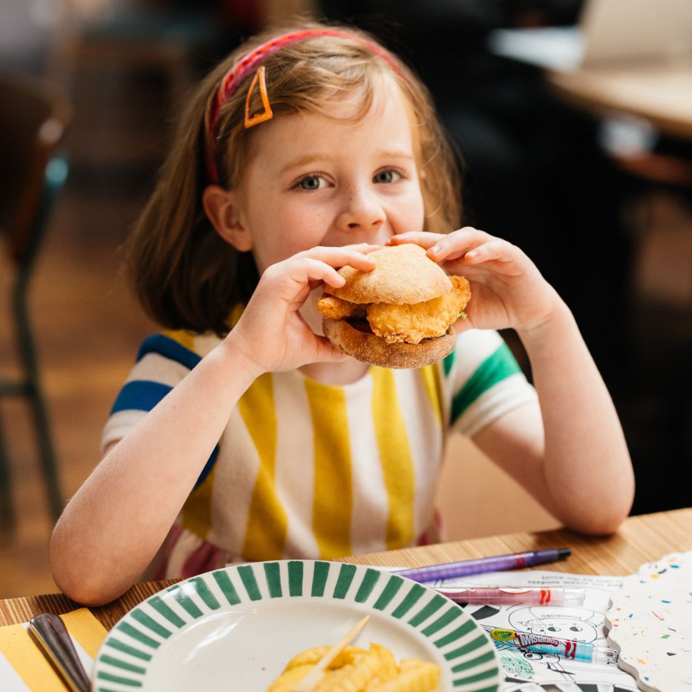 young girl biting into ask italian chicken sandwich
